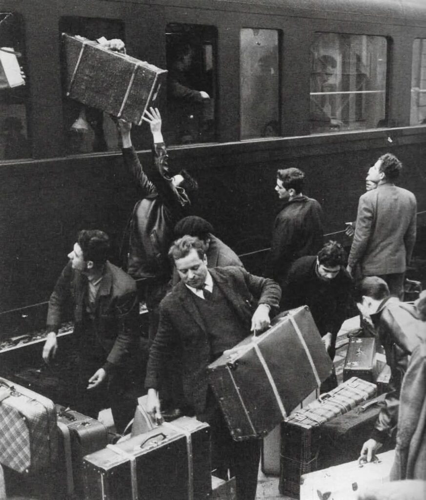Emigrantes españoles cargando maletas en un tren durante la emigración laboral hacia Europa.