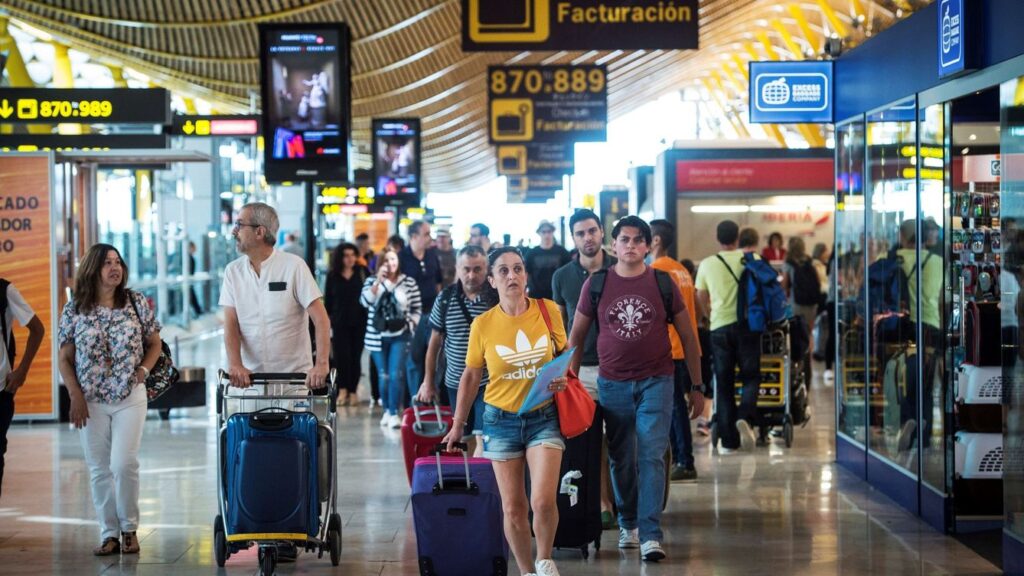 Personas con maletas en un aeropuerto de España, símbolo de los movimientos migratorios actuales.